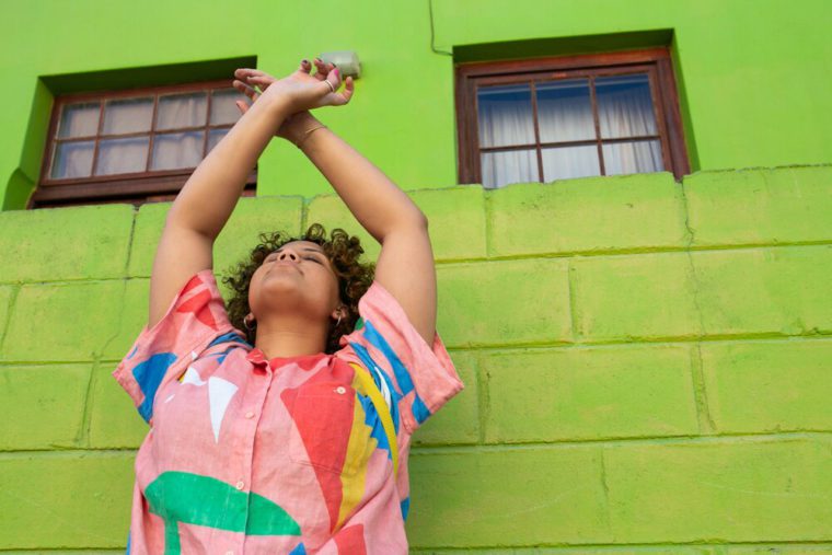 pic of youth against green wall with hands up