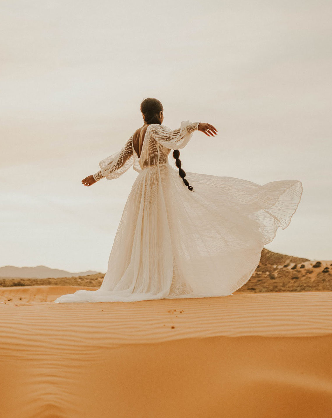 Woman wearing a white dress in the middle of a dessert