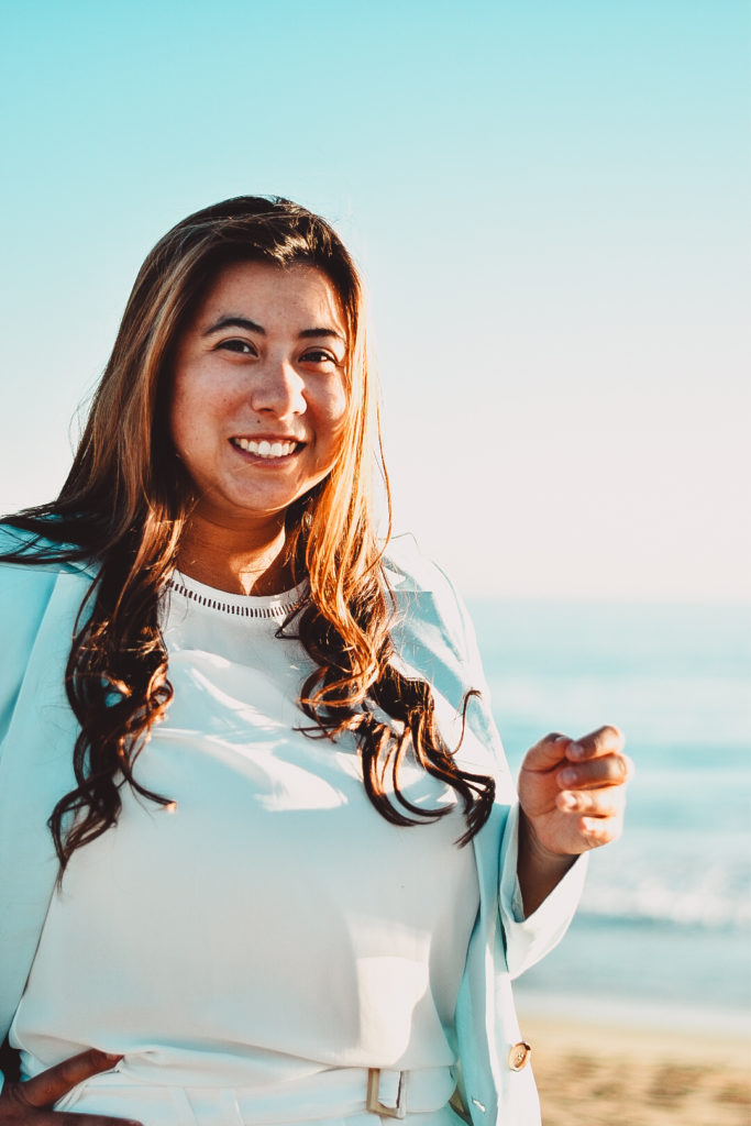 Photo of the author, Abigail Welcom, smiling on the beach in a white shirt and light blue blazer